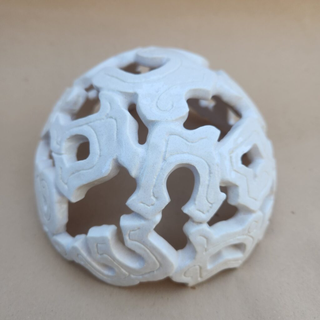 A spherical object with intricate cut-out designs resembling letters or characters from the Khmer language.