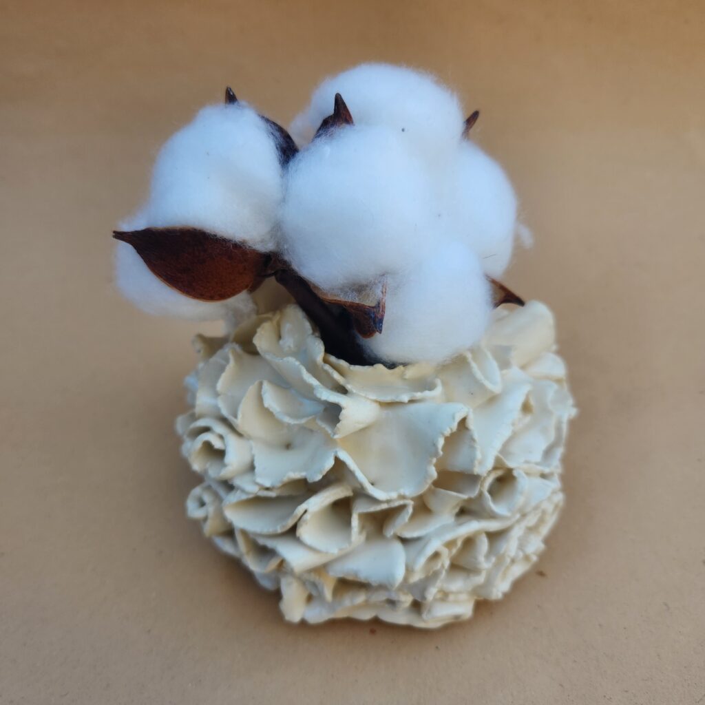 A decorative item featuring cotton blooms atop a textured base merging hand-building with wheel throwing.